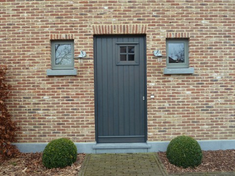 Zwart gebeitste houten pastorie inkomdeur met kijkvenstertje door Winfera in Hasselt geplaatst.