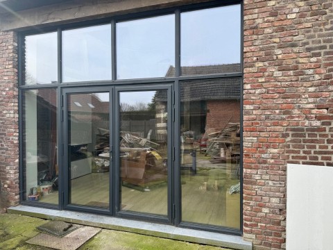 Achtergevel inkom in aluminium zwart steellook in een hoeve in Oudsbergen